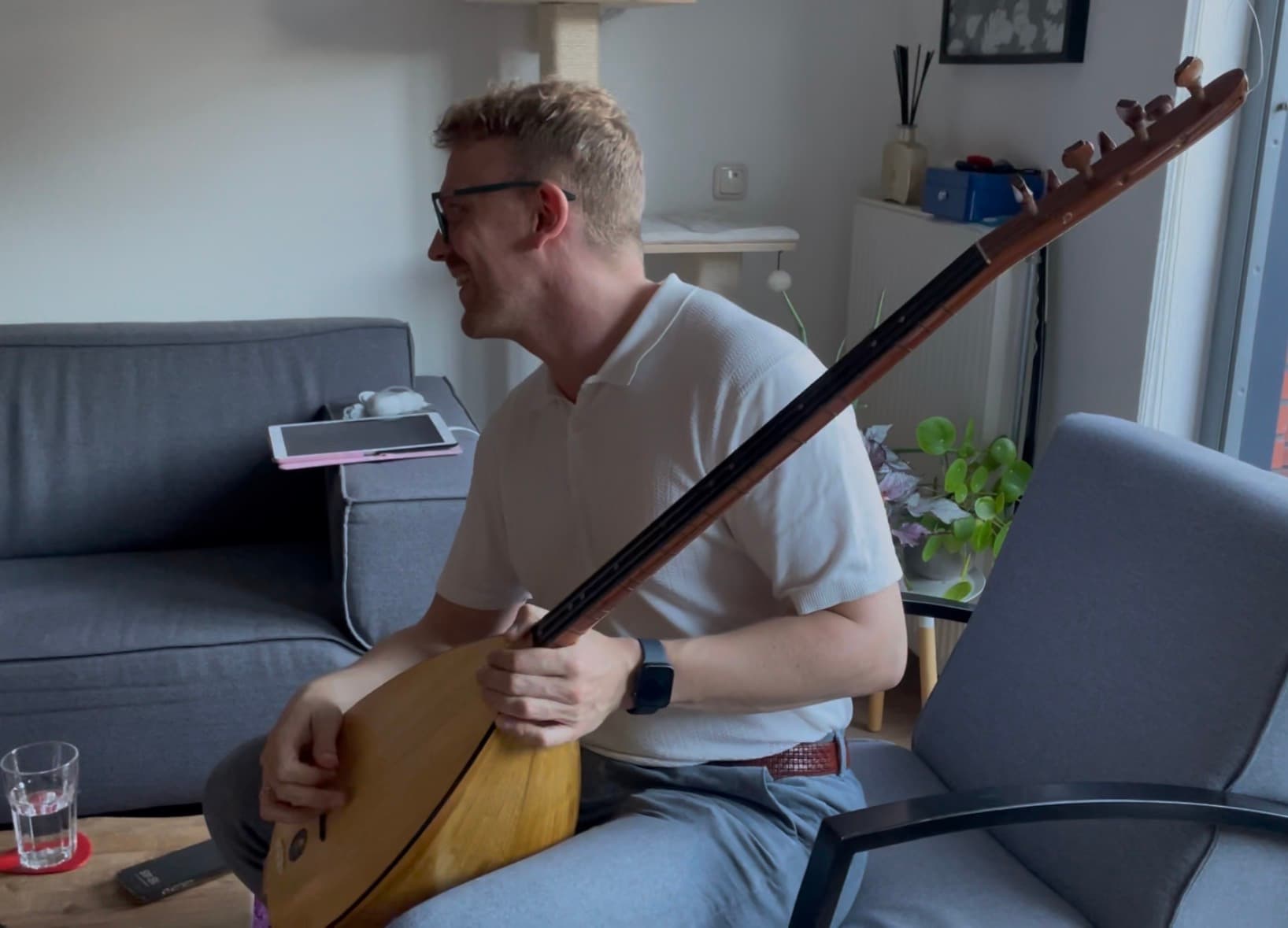 Tomas at home, laughing, holding a bağlama